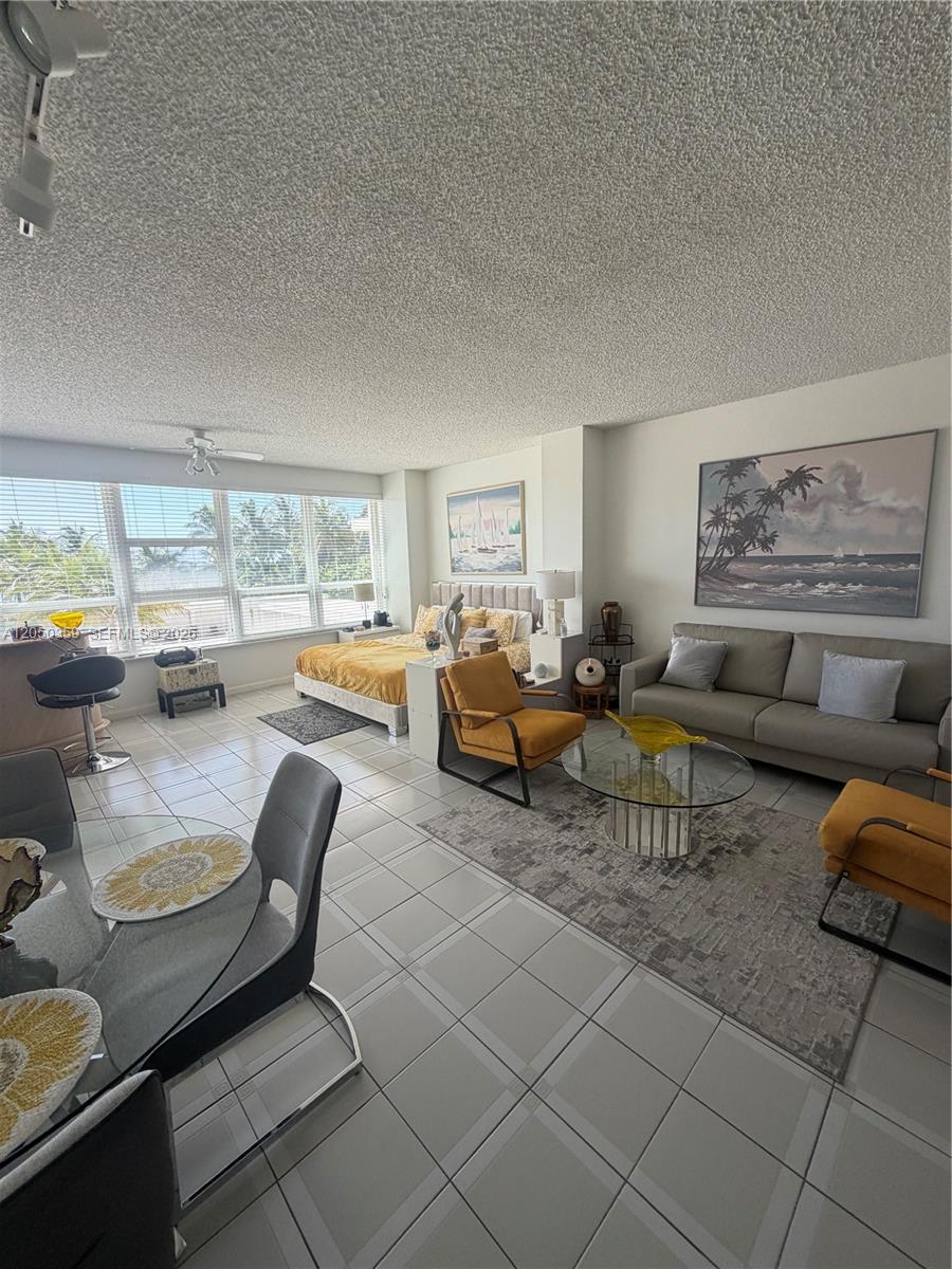 An open-concept living and bedroom area features tiled floors, a sofa, and large windows — 4925 Collins Ave # 2D, Miami Beach FL 33140, MIAMI BEACH, FL