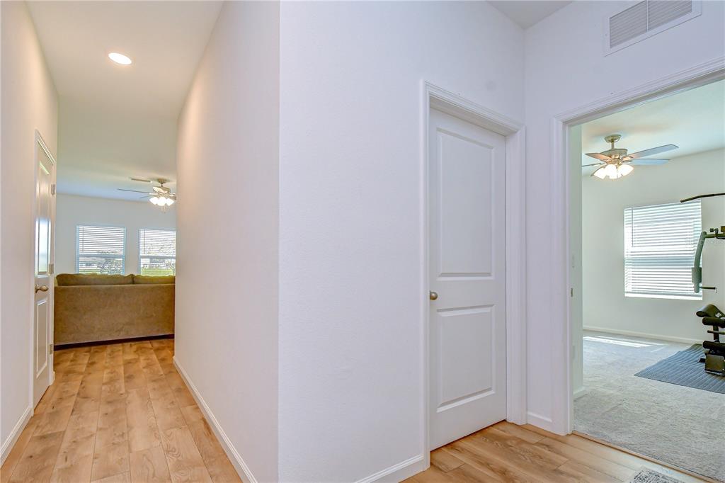 A hallway with wood-look flooring leads to a living area and a carpeted room — 35651 BUTTONWEED TRAIL, ZEPHYRHILLS, FL