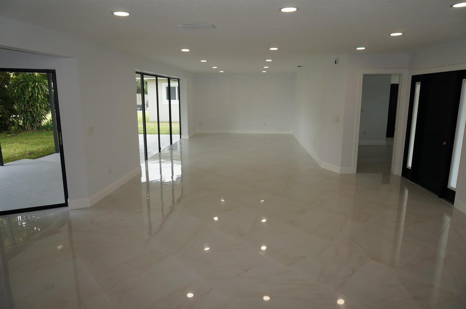 An empty room with white walls, recessed lighting, and polished marble-look tile flooring — 1513 39th Street, West Palm Beach FL 33407, WEST PALM BEACH, FL