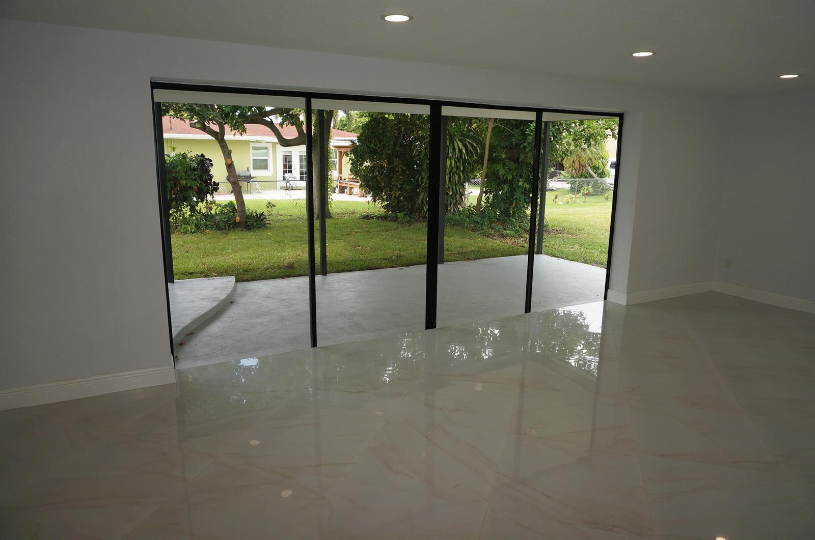 A room with polished marble-look tile floors and a large sliding glass door to a patio — 1513 39th Street, West Palm Beach FL 33407, WEST PALM BEACH, FL