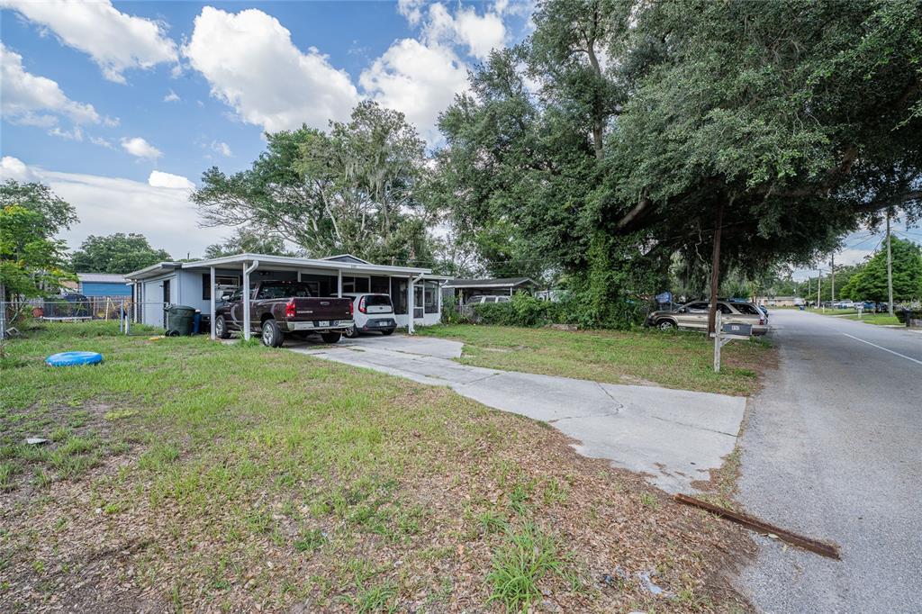 A single-story house with a carport and driveway sits on a grassy lot with trees — 490 W ETHELENE STREET, BARTOW, FL