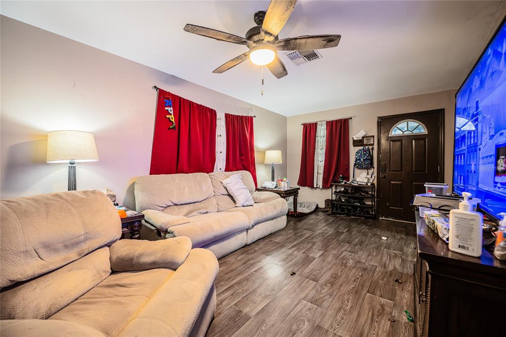 A living room features light-colored sofas, wood-look flooring, red curtains, and a ceiling fan — 490 W ETHELENE STREET, BARTOW, FL