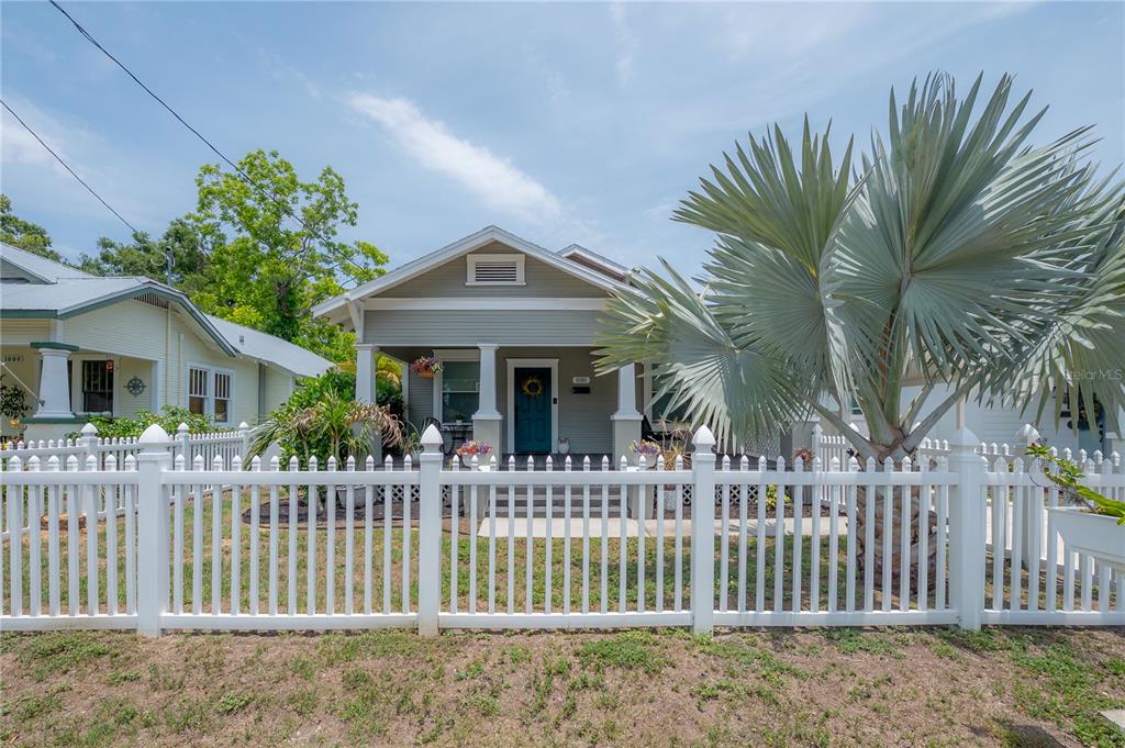 A white picket fence surrounds the front yard of a gray bungalow with a porch — 1010 E CURTIS STREET, TAMPA, FL