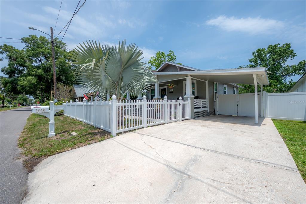 A single-story house with a white picket fence, a concrete driveway, and a carport — 1010 E CURTIS STREET, TAMPA, FL