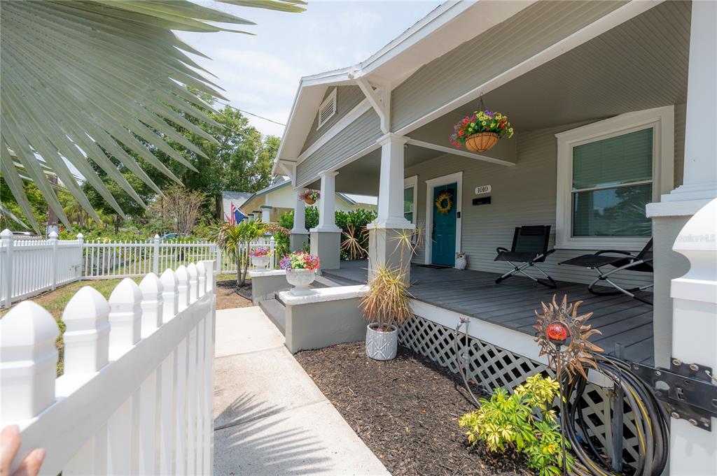 A white picket fence leads to a covered front porch with gray decking and columns — 1010 E CURTIS STREET, TAMPA, FL