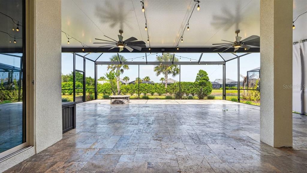A spacious covered patio features stone tile flooring, two ceiling fans, and string lights — 842 ATTITUDE AVENUE, DAYTONA BEACH, FL