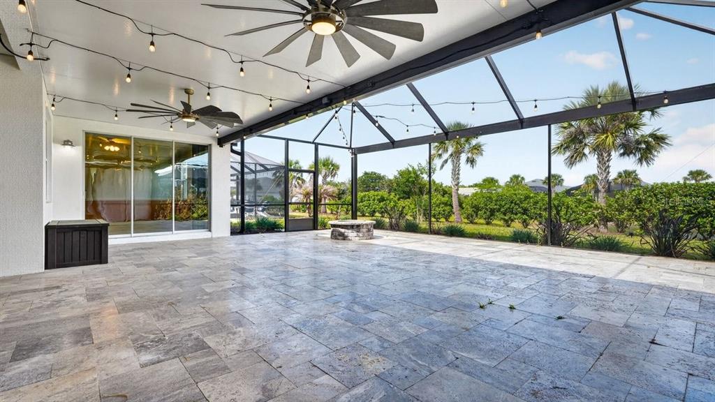 A spacious covered patio features stone tile flooring, ceiling fans, string lights, and a screened enclosure — 842 ATTITUDE AVENUE, DAYTONA BEACH, FL