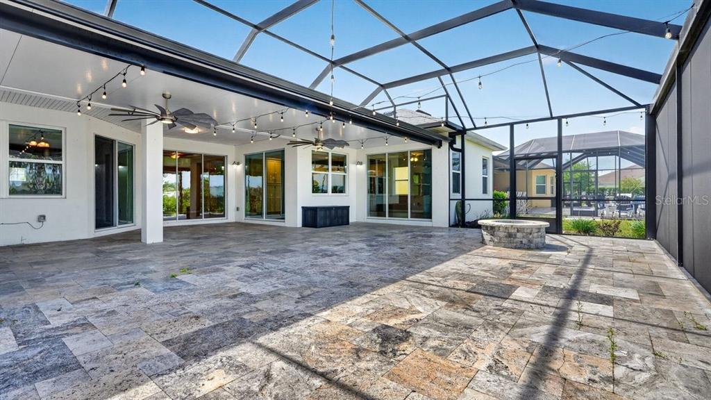 A covered patio features stone tile flooring, a fire pit, and a screened-in enclosure — 842 ATTITUDE AVENUE, DAYTONA BEACH, FL