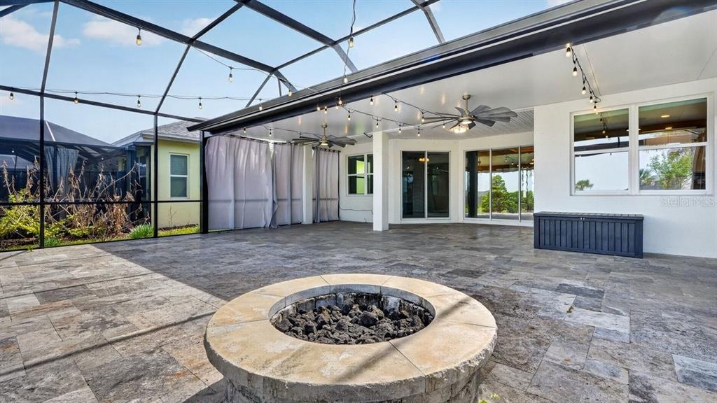 A covered patio features a stone fire pit, tile flooring, and a screened enclosure — 842 ATTITUDE AVENUE, DAYTONA BEACH, FL