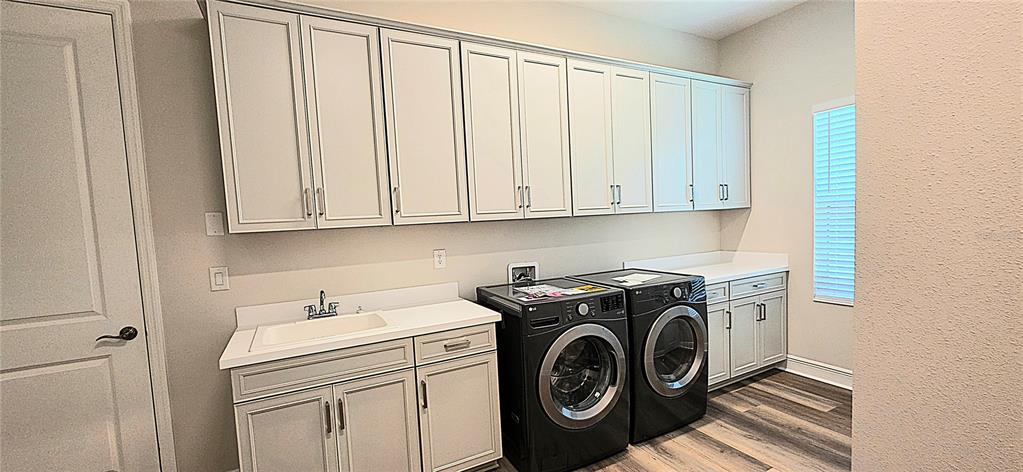 A laundry room features light gray cabinetry, a utility sink, and black front-load appliances — 35436 BIG HAWK DRIVE, ZEPHYRHILLS, FL