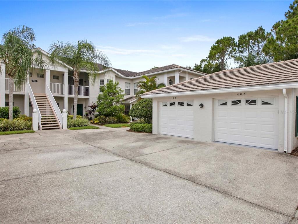 A two-story apartment building exterior with a detached two-car garage and a concrete driveway — 901 ADDINGTON COURT UNIT 203, VENICE, FL
