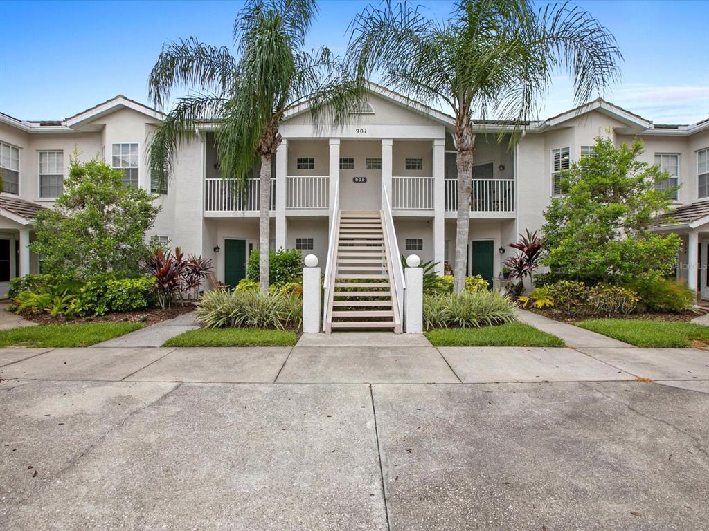 A two-story apartment building features a central staircase leading to an upper-level balcony — 901 ADDINGTON COURT UNIT 203, VENICE, FL