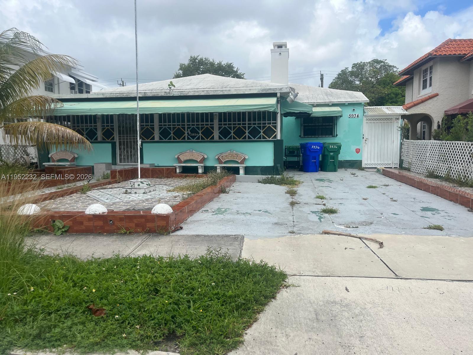 A single-story turquoise house features a front porch, a paved driveway, and a tiled courtyard — 5934 NE 4th Ct, Miami FL 33137, MIAMI, FL