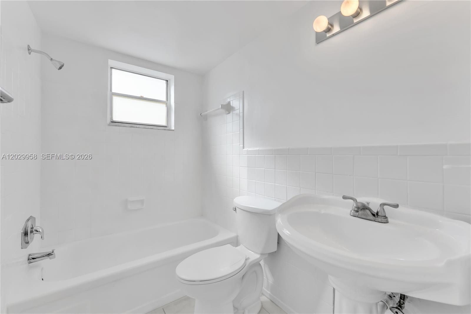 A white bathroom features a pedestal sink, a toilet, and a tiled shower-tub combination — 2145 Pierce St # 305, Hollywood FL 33020, HOLLYWOOD, FL