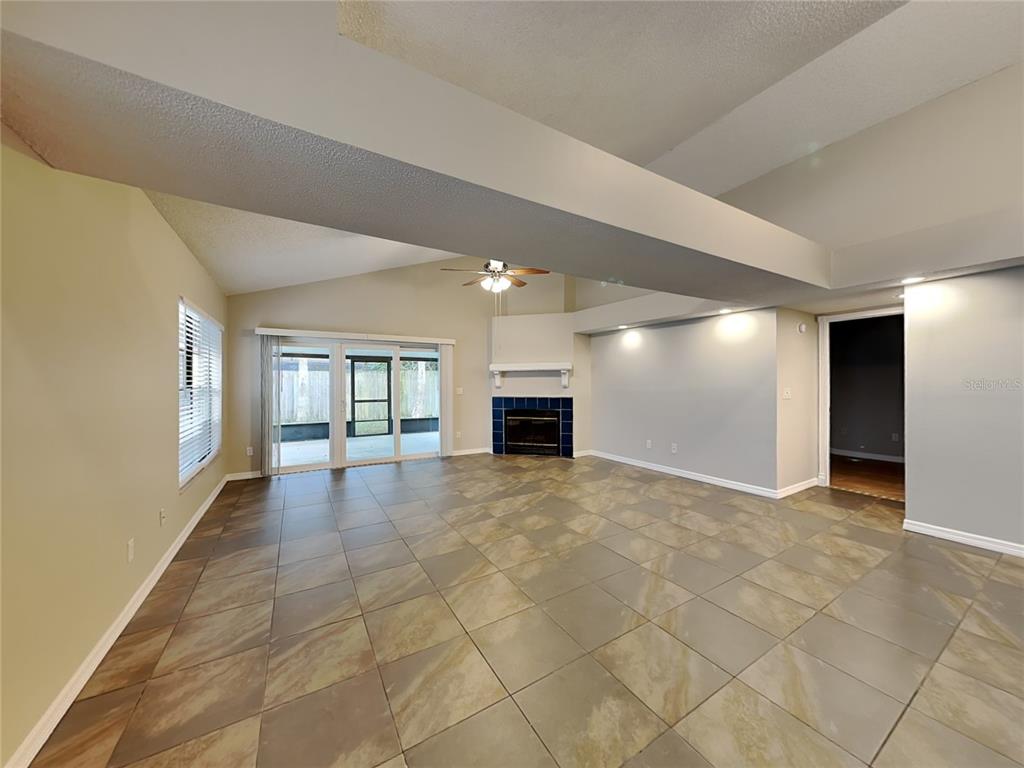 A living room with tile flooring, a corner fireplace, and sliding glass doors to a patio — 419 E SPRINGTREE WAY, LAKE MARY, FL