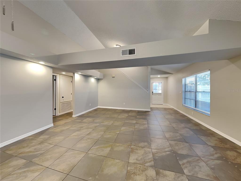 An open living area features large square floor tiles, light gray walls, and a prominent beam — 419 E SPRINGTREE WAY, LAKE MARY, FL