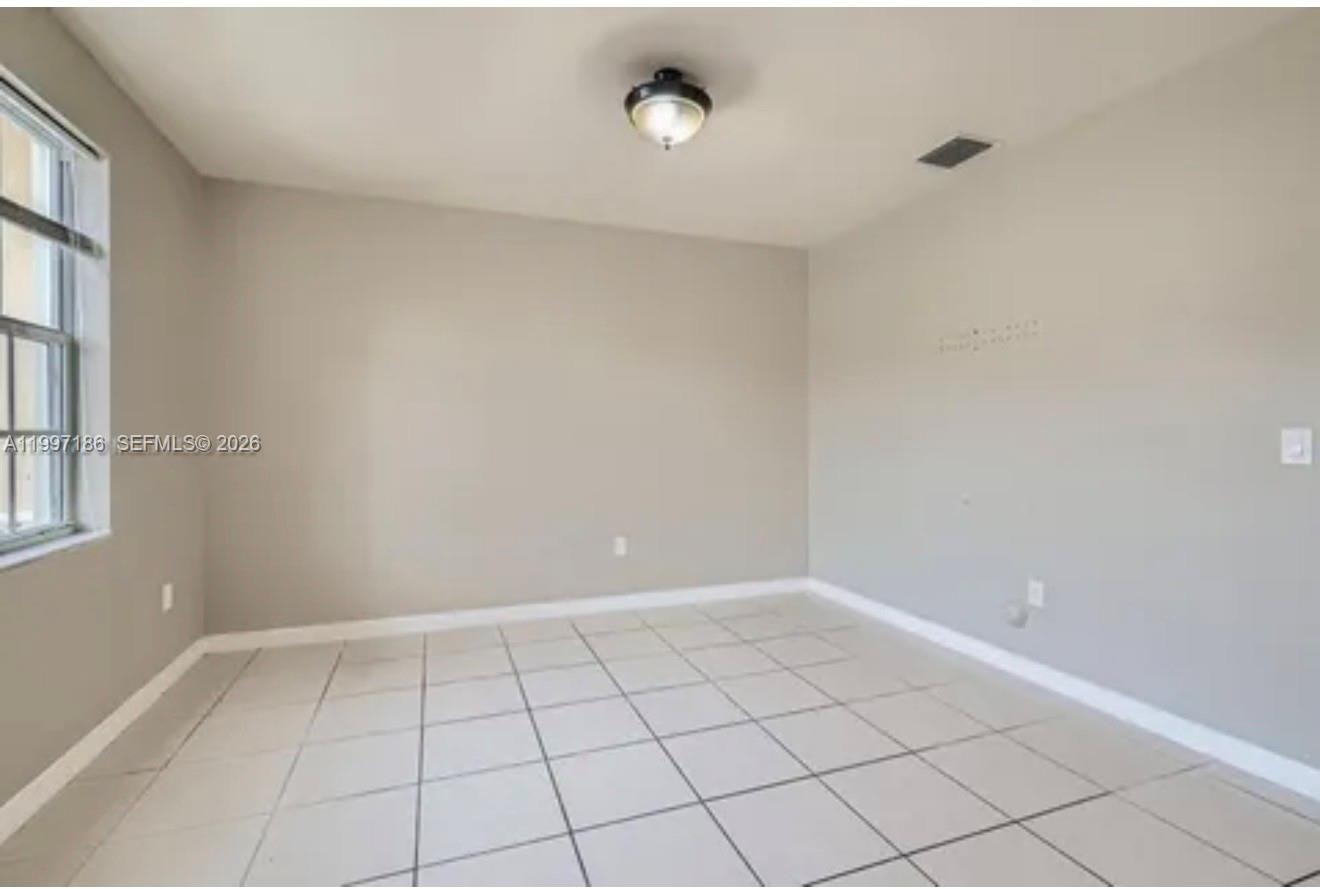 An empty room with light gray walls, white baseboards, and large square floor tiles — 9125 SW 227th St # 1, Cutler Bay FL 33190, CUTLER BAY, FL