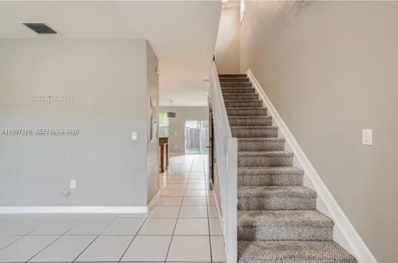 A carpeted staircase leads to an upper floor next to a tiled entryway and hallway — 9125 SW 227th St # 1, Cutler Bay FL 33190, CUTLER BAY, FL
