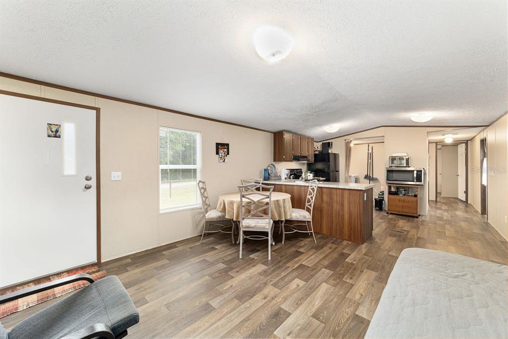 A kitchen and dining area with wood-look flooring, a breakfast bar, and a round table — 11776 NW 21ST STREET, OCALA, FL