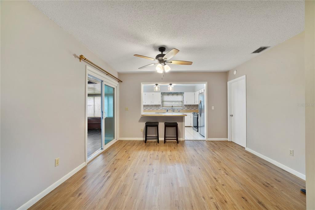 A dining area with wood-look flooring, a ceiling fan, and a pass-through to the kitchen — 146 MAYFAIR COURT, SANFORD, FL