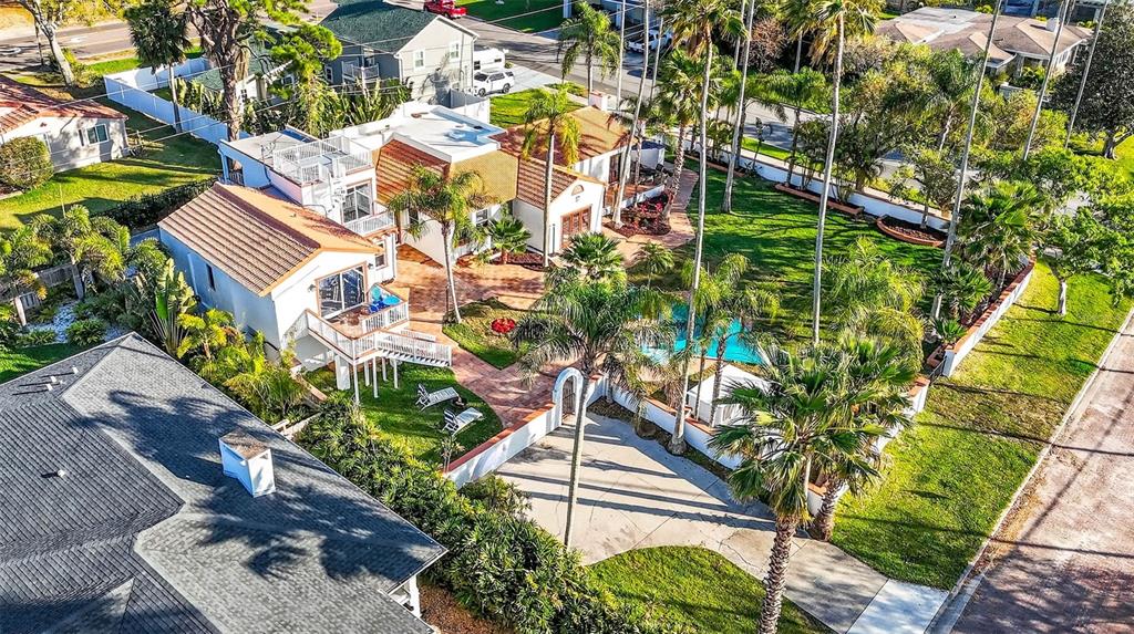 An aerial view shows a house with a tiled roof, pool, and palm-filled backyard — 236 SAN SALVADOR DRIVE, DUNEDIN, FL