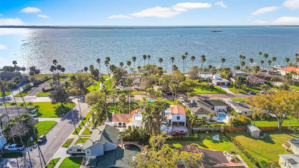 An aerial view shows several residential homes with swimming pools near a large body of water — 236 SAN SALVADOR DRIVE, DUNEDIN, FL