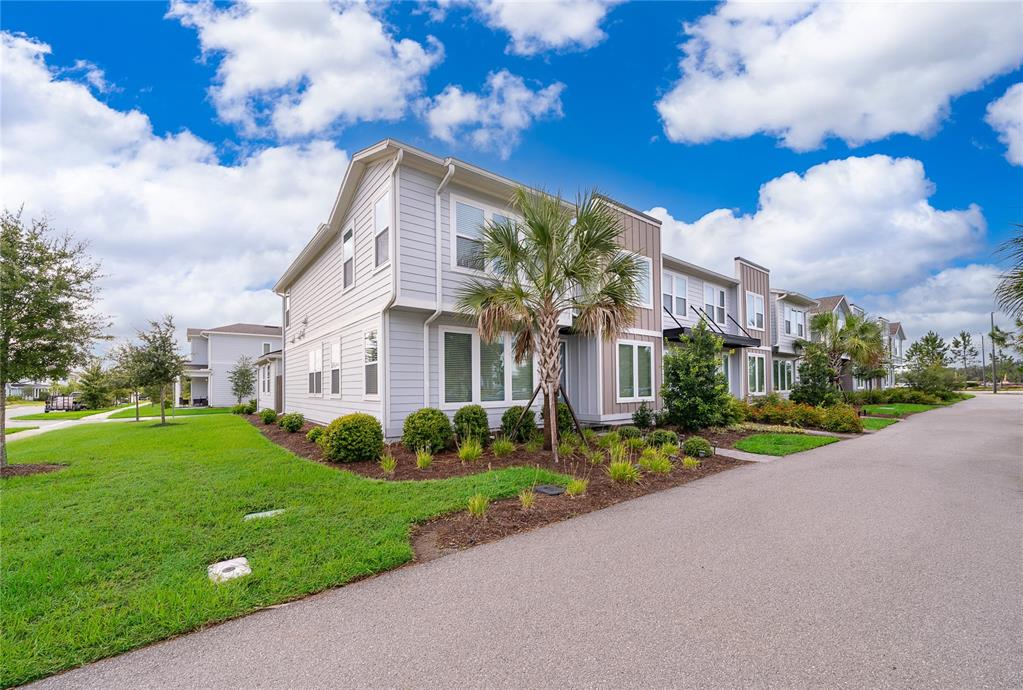 A multi-story townhouse with light gray siding and a palm tree in the front yard — 2929 VOYAGER AVENUE, ST CLOUD, FL