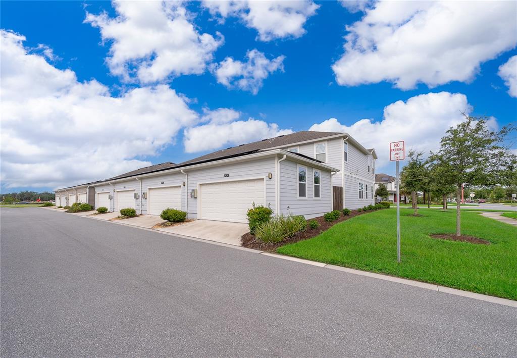 A row of light-colored townhomes with attached garages sits beside a grassy lawn — 2929 VOYAGER AVENUE, ST CLOUD, FL