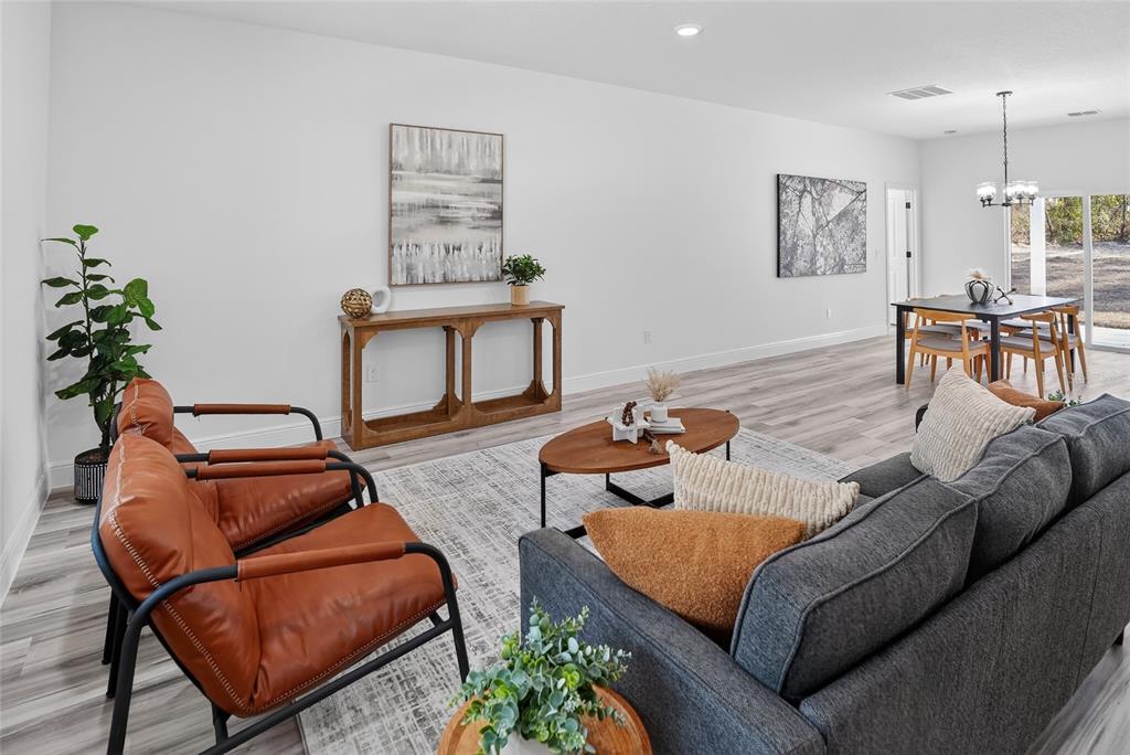 A living room with leather chairs, a grey sofa, and a dining area beyond — 7945 N JANEAUX DRIVE, CITRUS SPRINGS, FL