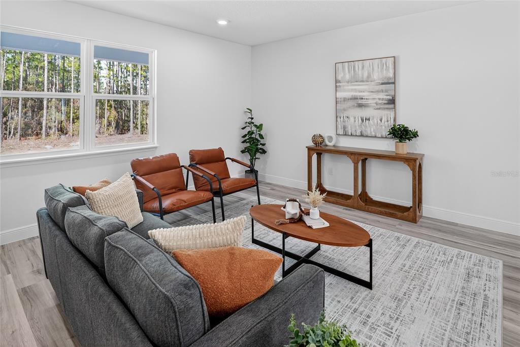 A living room features a gray sofa, two leather chairs, a coffee table, and wood flooring — 7945 N JANEAUX DRIVE, CITRUS SPRINGS, FL