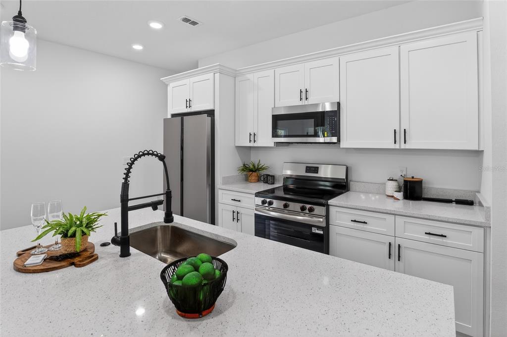 A modern kitchen features white cabinets, stainless steel appliances, and a large quartz island — 7945 N JANEAUX DRIVE, CITRUS SPRINGS, FL