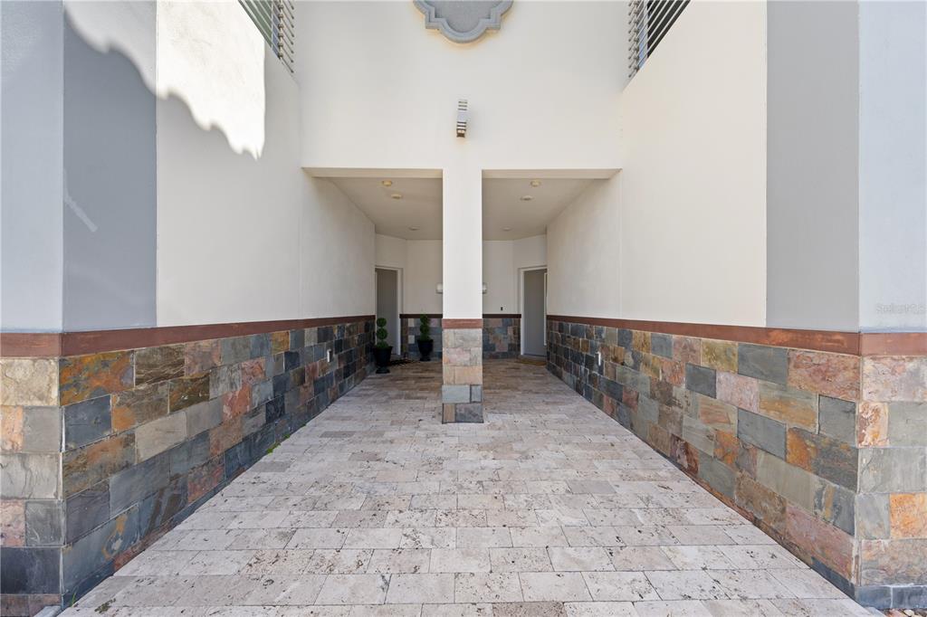 A covered entryway features stone-tiled walls, a paved floor, and a central support pillar — 1935 GREENBRIAR TERRACE, DAVENPORT, FL
