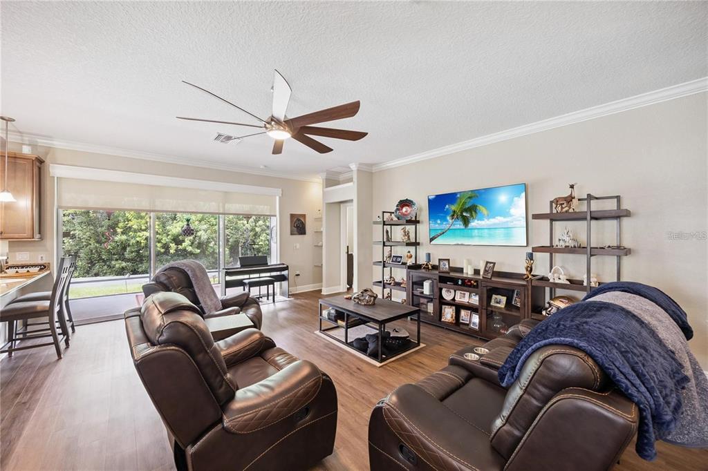A living room features brown leather recliners, a television, shelving, and wood-look flooring — 1923 BANNING BEACH ROAD, TAVARES, FL