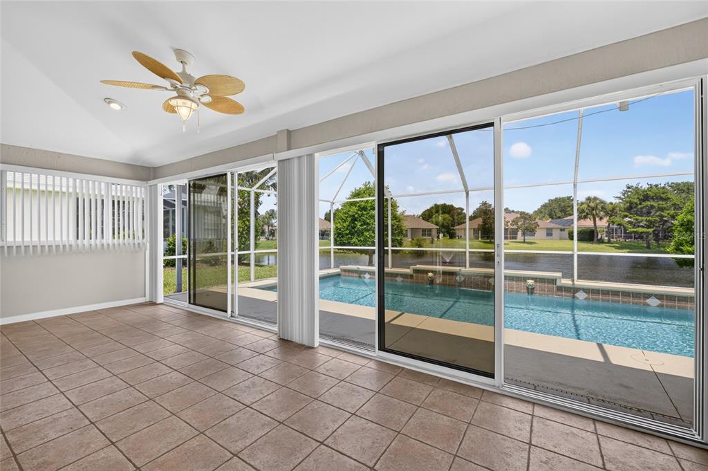 A tiled sunroom features sliding glass doors opening to a screened-in pool and lake view — 1301 FLAGSHIP COURT, ST AUGUSTINE, FL