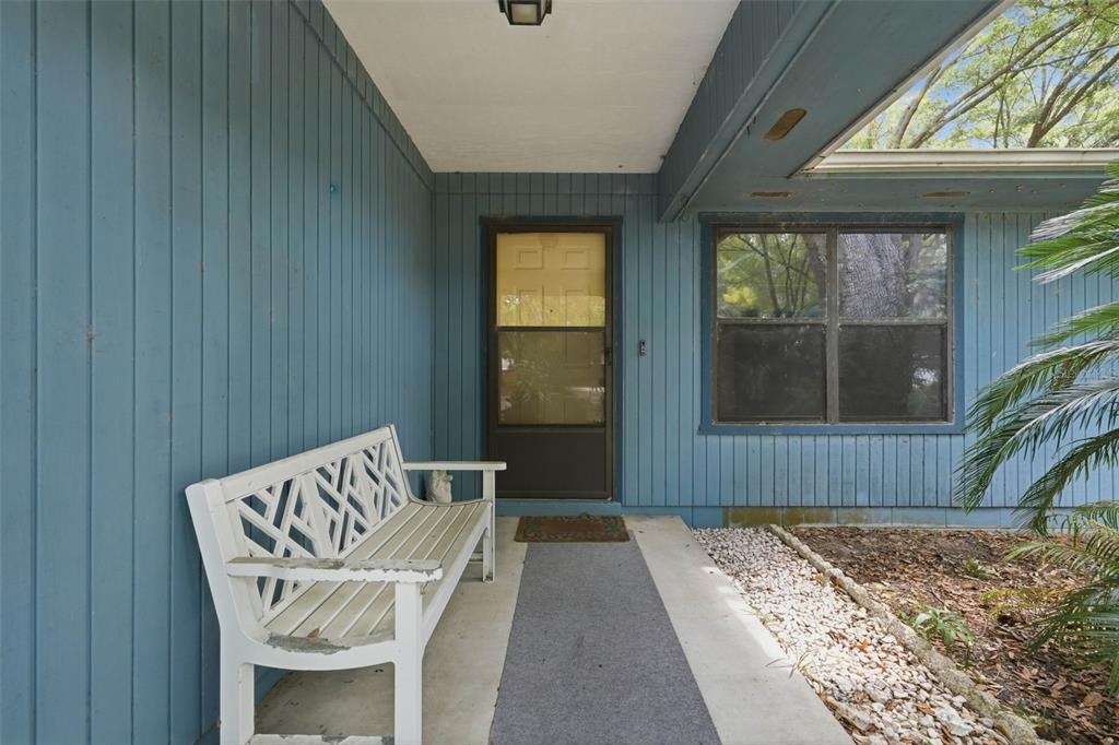 A blue-sided house exterior features a covered porch with a white bench and front door — 31 ALMOND PASS DRIVE, OCALA, FL
