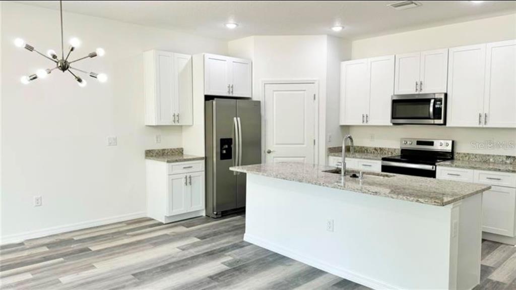 A kitchen features white cabinets, granite countertops, stainless steel appliances, and wood-look flooring — 2951 W YORKSHIRE PLACE, CITRUS SPRINGS, FL