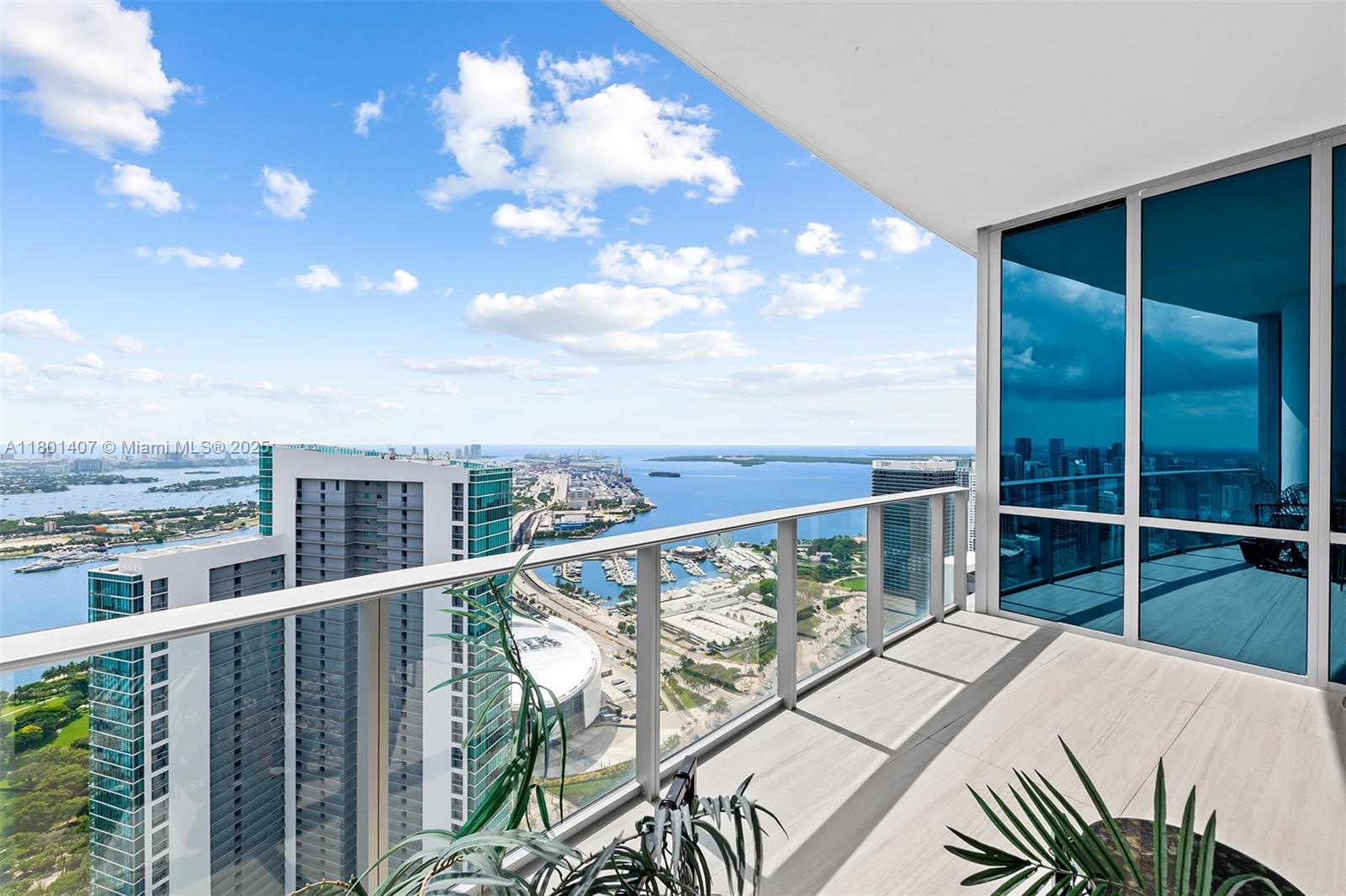 A high-rise balcony with glass railings overlooks a city skyline, harbor, and the ocean — 851 NE 1st Ave # 5401, Miami FL 33132, MIAMI, FL
