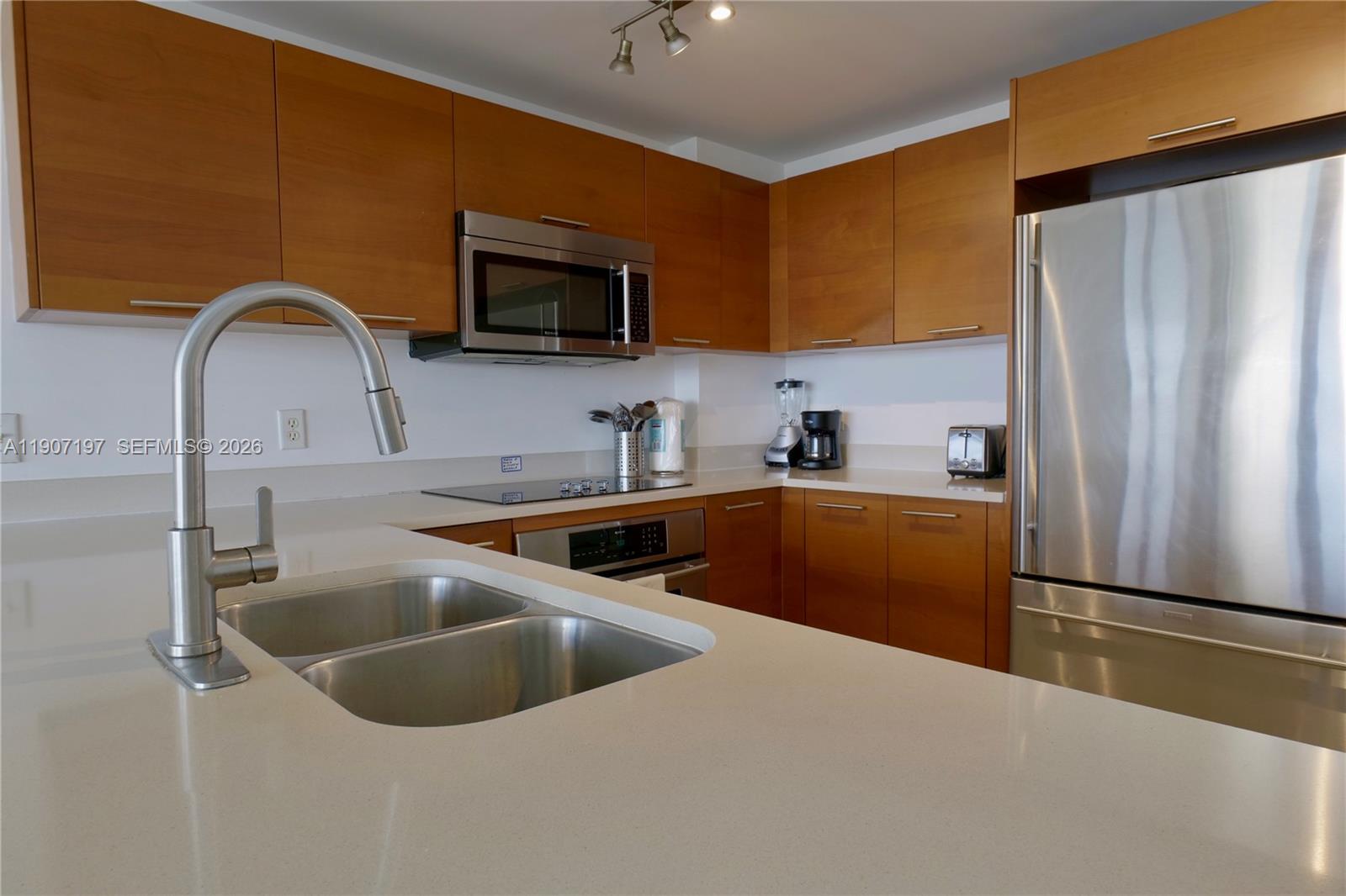 A modern kitchen features wood cabinets, stainless steel appliances, and light-colored quartz countertops — 3250 NE 1st Ave # 910, Miami FL 33137, MIAMI, FL