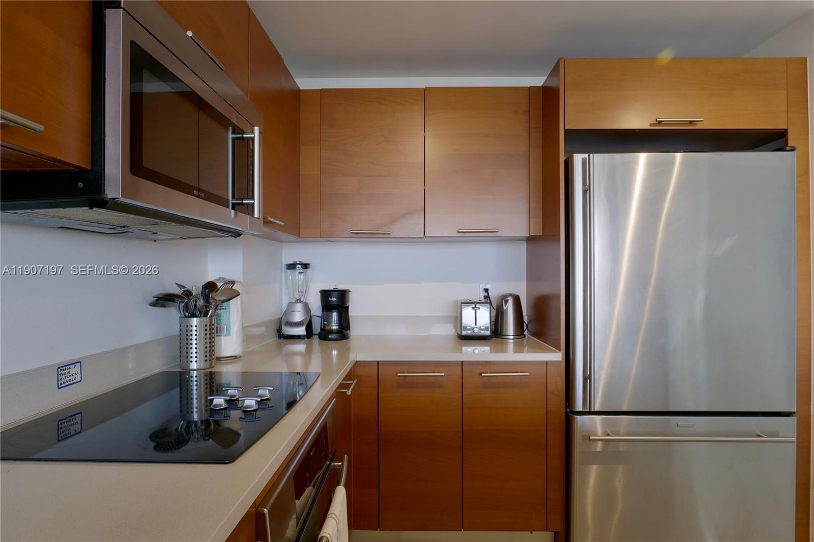A kitchen features wood cabinets, stainless steel appliances, and light-colored countertops — 3250 NE 1st Ave # 910, Miami FL 33137, MIAMI, FL