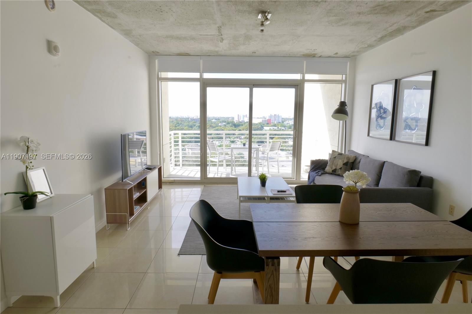 A modern living and dining area features tile floors, a concrete ceiling, and a balcony — 3250 NE 1st Ave # 910, Miami FL 33137, MIAMI, FL