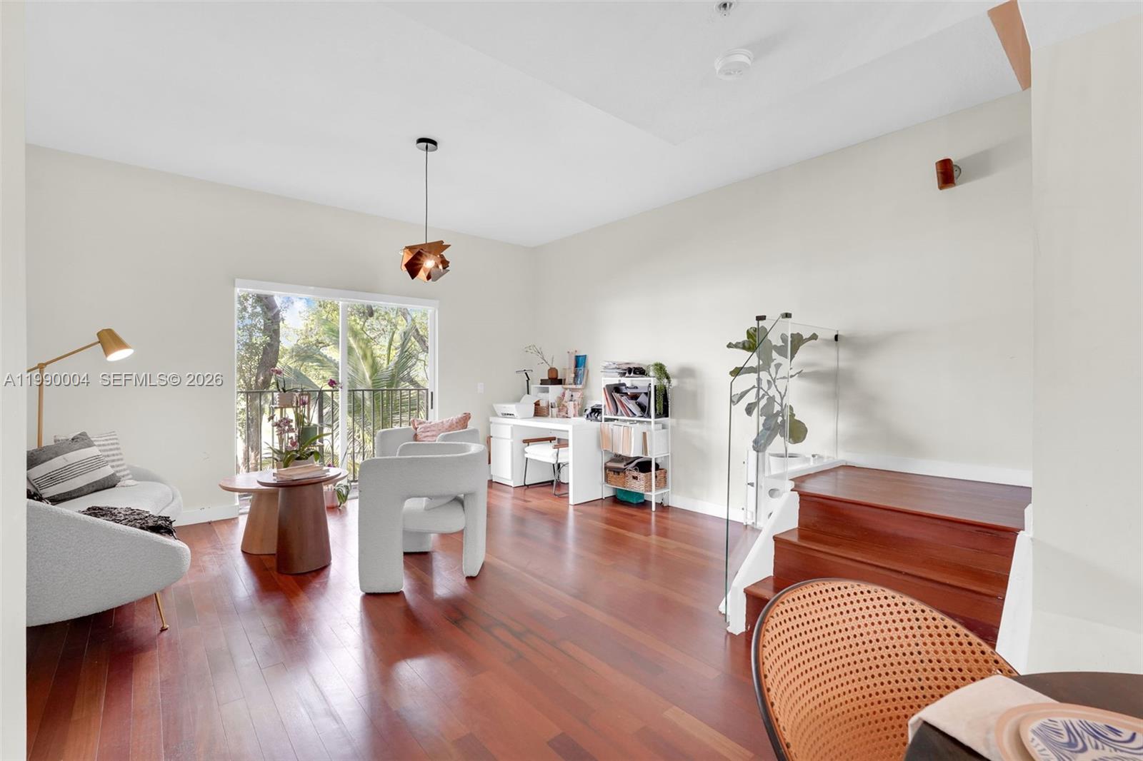 A living room with hardwood floors, a desk area, and a staircase with glass railing — 738 NE 90th St # 207, Miami FL 33138, MIAMI, FL