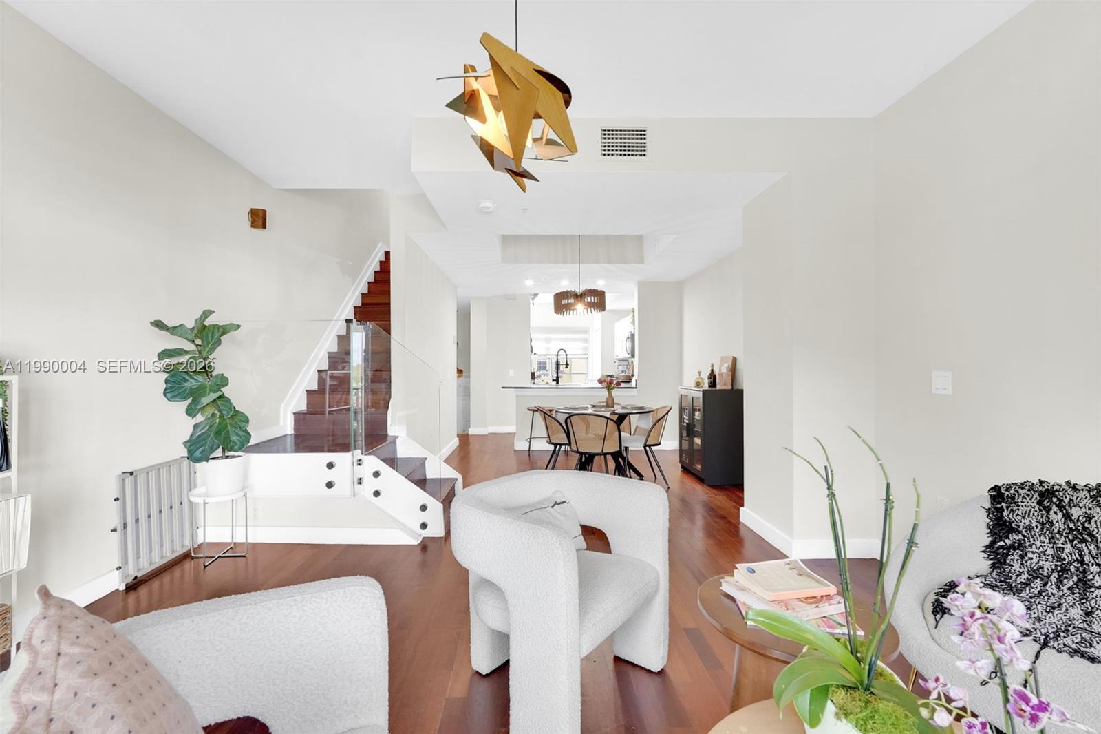 A living room with hardwood floors, a staircase, and a dining area in the background — 738 NE 90th St # 207, Miami FL 33138, MIAMI, FL