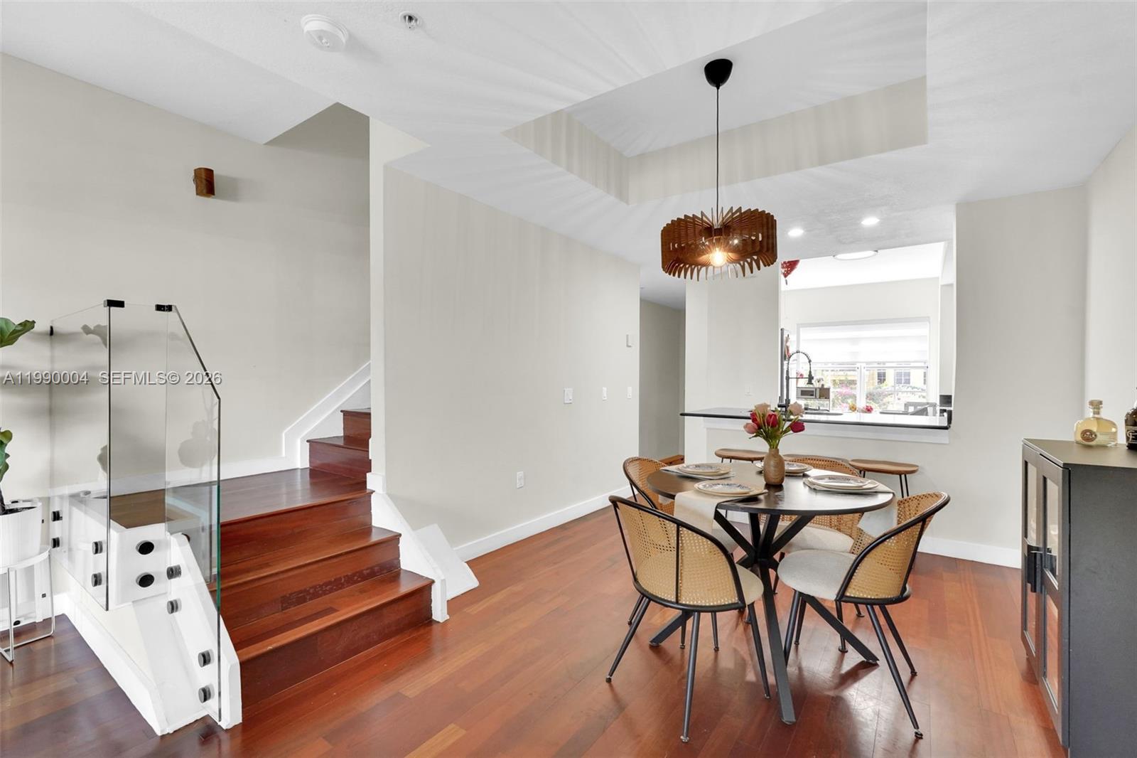 A dining area with a round table and wooden stairs with a glass railing — 738 NE 90th St # 207, Miami FL 33138, MIAMI, FL