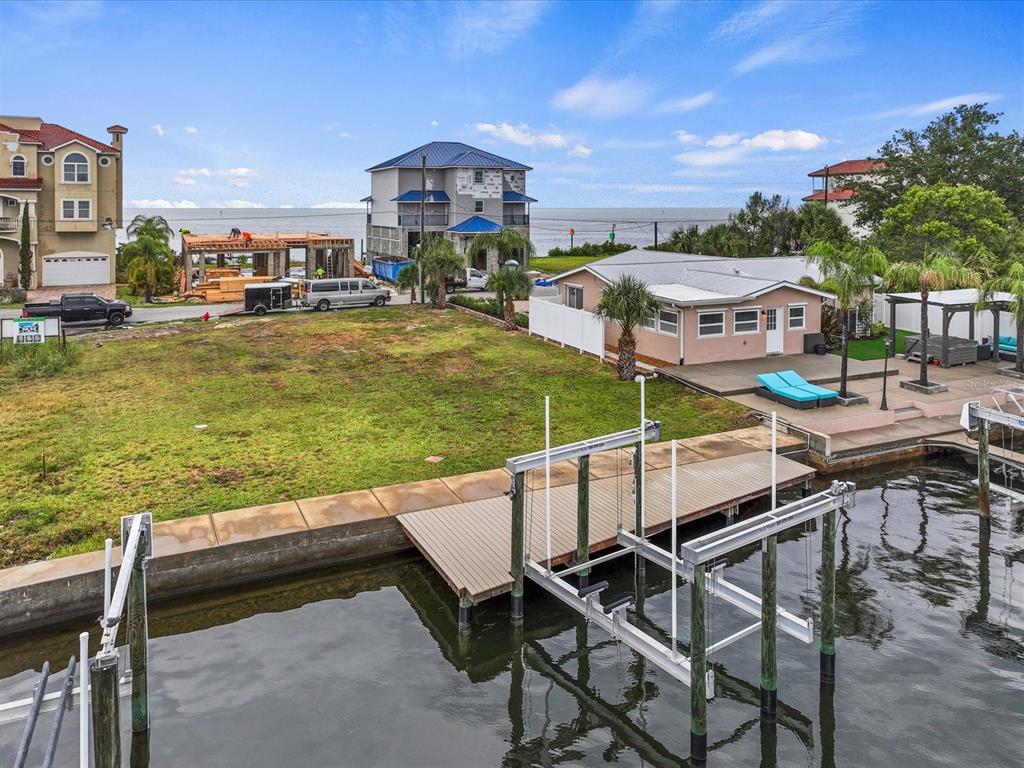 An aerial view shows a waterfront lot with a boat lift, dock, and nearby houses — 6200 LONNIE LEE LANE, HUDSON, FL