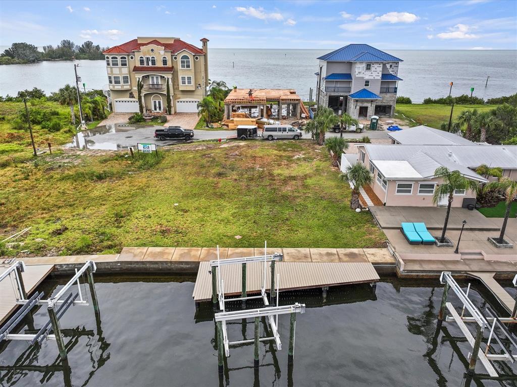 An aerial view shows a vacant waterfront lot situated between three houses and a boat dock — 6200 LONNIE LEE LANE, HUDSON, FL