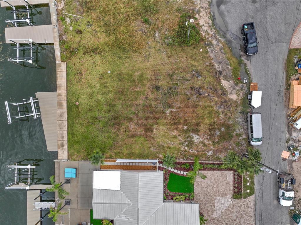 An aerial view shows a vacant waterfront lot with a boat dock and adjacent house — 6200 LONNIE LEE LANE, HUDSON, FL