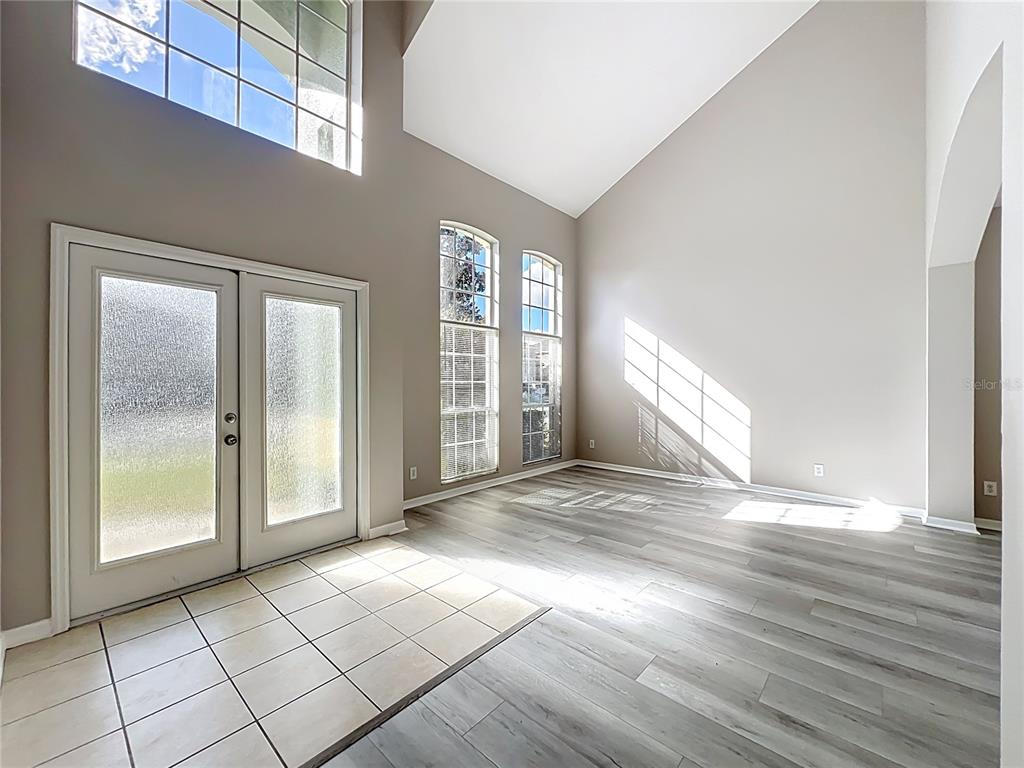 An entryway features a tiled floor, light wood-look flooring, tall windows, and a vaulted ceiling — 33411 TERRAGONA DRIVE, SORRENTO, FL