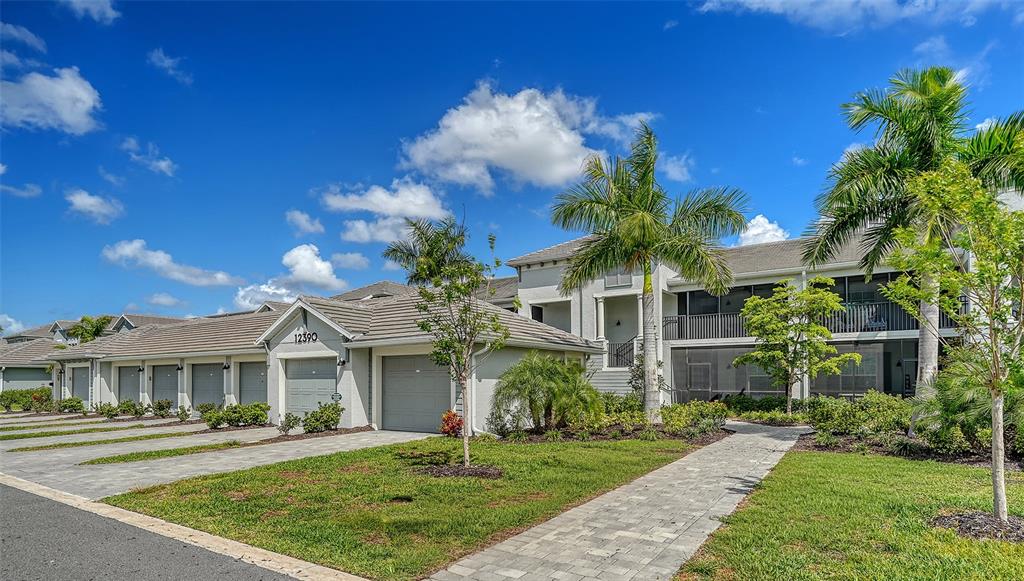 A row of attached residential garages with a paved walkway and palm trees outside — 12390 WELLEN GOLF STREET UNIT 107, VENICE, FL