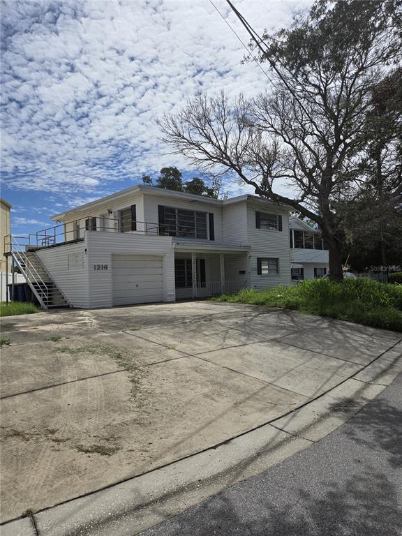 A two-story white house with a garage, an exterior staircase, and a concrete driveway — 1216 FRANKLIN CIRCLE, CLEARWATER, FL