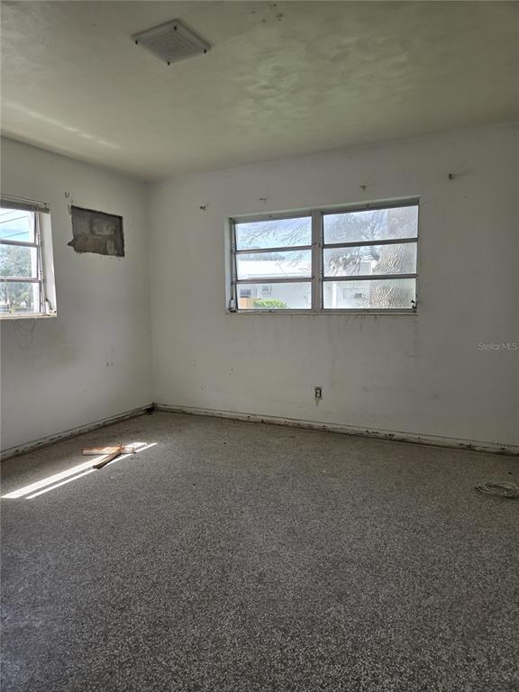 An empty bedroom features white walls, a speckled floor, and two windows — 1216 FRANKLIN CIRCLE, CLEARWATER, FL